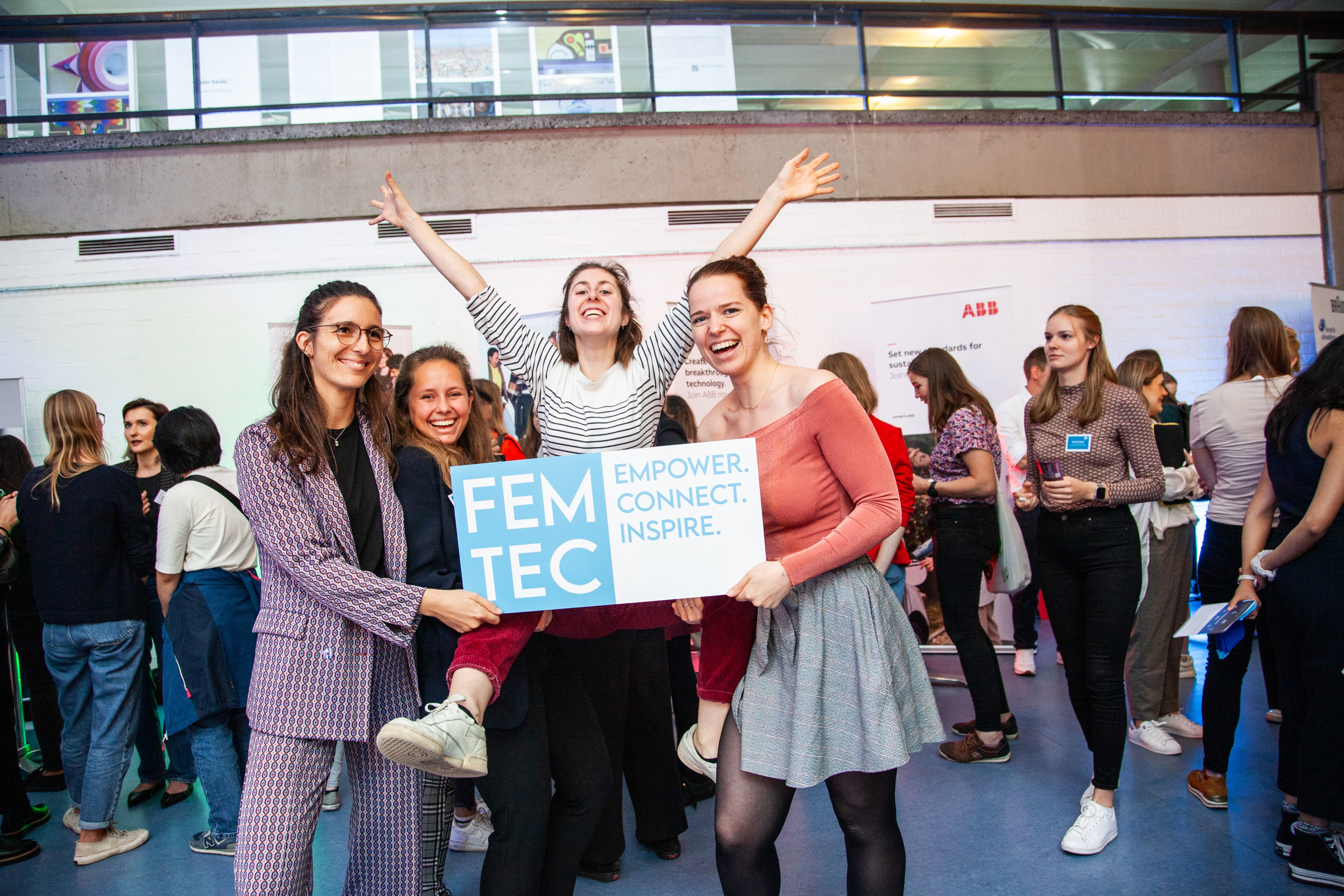 Four female students enthusiastically hold a sign with the Femtec logo.